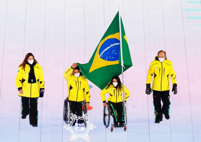 Four people wearing Brazil's yellow winter jacket is parading during the Beijing 2022 Opening Ceremony